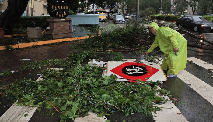 A man picks up fallen store signs after Typhoon Krathon made landfall in Kaohsiung, Taiwan October 3, 2024. — Reuters