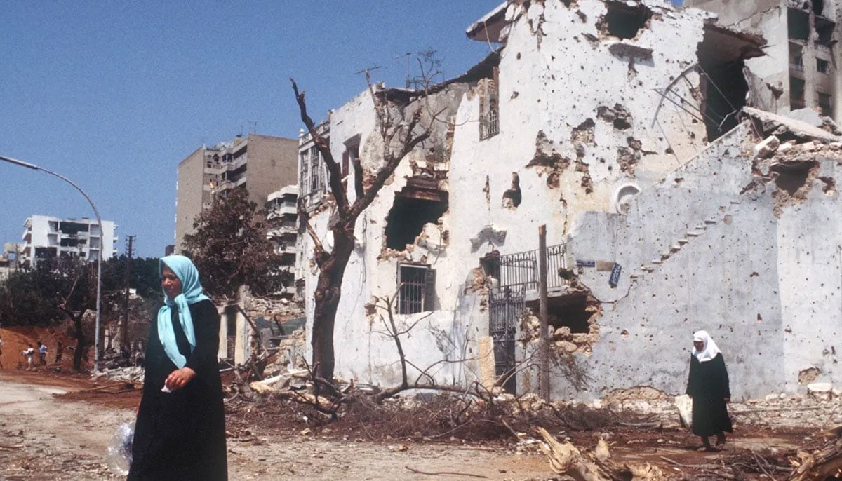 Residents of West Beirut crossing a street demolished by Israeli shelling, Lebanon, July 24, 1982. — AFP