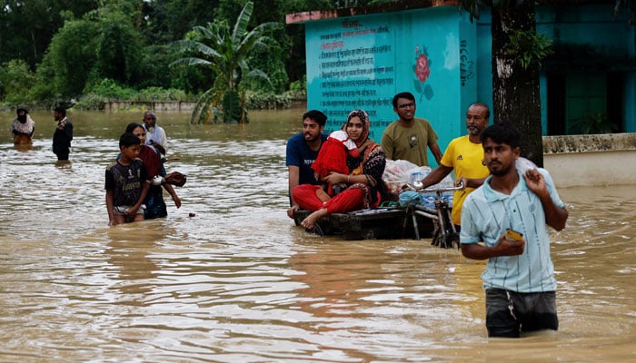 People move a cart with a woman and a child through a flooded street, amid severe flooding in the Fazilpur area of Feni, Bangladesh on August 26, 2024. — Reuters