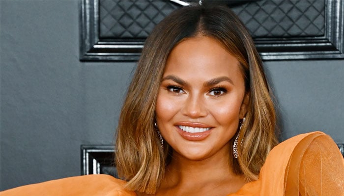 Chrissy Teigen teases new lower back tattoo in a latex gown