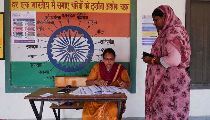 A booth-level officer helps a woman verify her name in the voting list outside a polling station during the state assembly elections, in Karnal, in the northern state of Haryana, India, on October 5, 2024. — Reuters