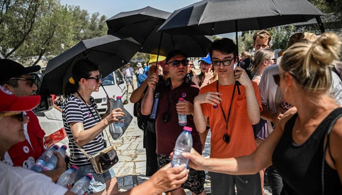 Hellenic Red Cross workers distribute bottles of water to visitors outside the Acropolis in Athens on July 13, 2023, as Greece hits high temperatures. — AFP