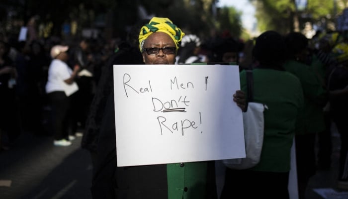 A protester holds a sign in front of the Johannesburg Stock Exchange in Sandton, Johannesburg, on September 13, 2019 during a protest following the rape and murder of a 19-year-old university student in Cape Town. —AFP