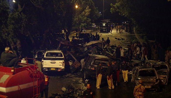 Police officers and paramilitary soldiers gather near the wreckage of vehicles after an explosion near Jinnah International Airport in Karachi, on October 6, 2024. — Reuters