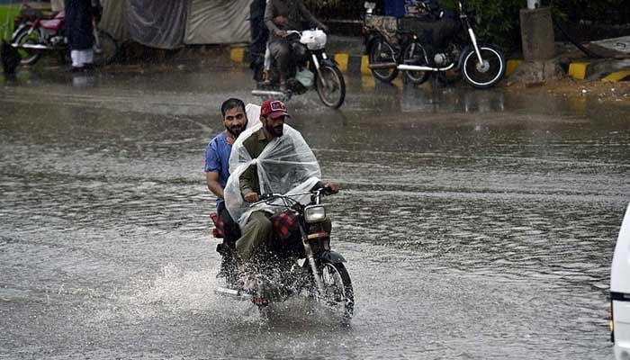 Motorcyclists ride a bike as rain continues. — APP/File