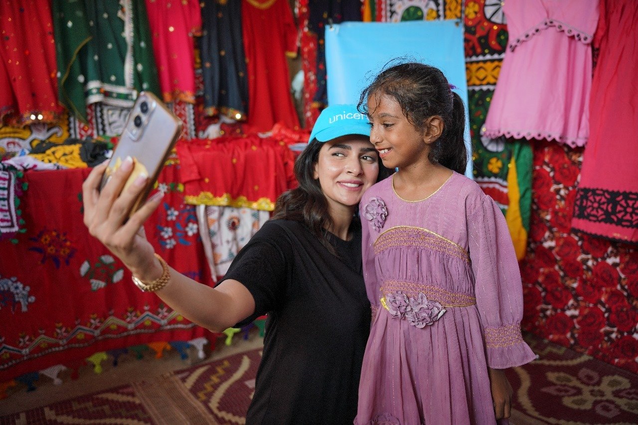 Actor Saba Qamar takes a selfie with a little girl at a womens clothing stall. —Unicef