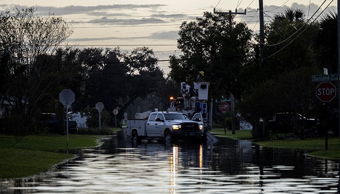 Utility workers repair a power line on a flooded street after Hurricane Milton made landfall in South Daytona, Florida, US, October 11, 2024. — Reuters