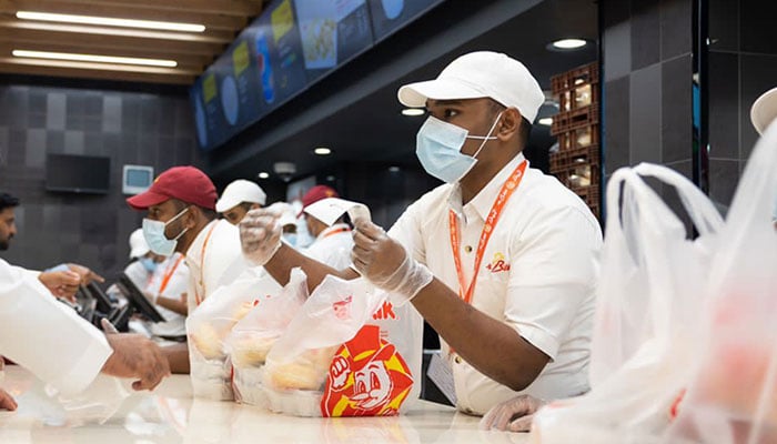 In this undated photo, salesmen are dealing with customers at an outlet of Al Baik Food System Company. — AlBaik website/File