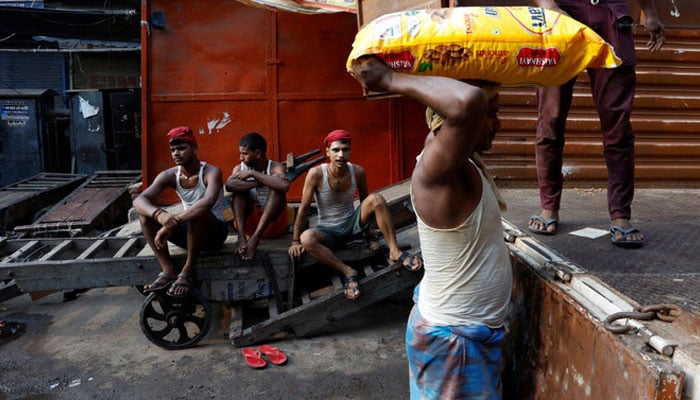 A labourer unloads a sack of almonds from a supply truck as other labourers wait for their turn, at a wholesale market in the old quarters of Delhi, India, July 22, 2024. — Reuters