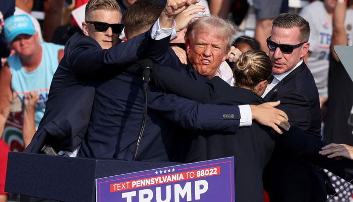 Republican presidential candidate and former US President Donald Trump gestures with a bloodied face while he is assisted by US Secret Service personnel after he was shot in the right ear during a campaign rally at the Butler Farm Show in Butler, Pennsylvania, US, July 13, 2024 — Reuters.