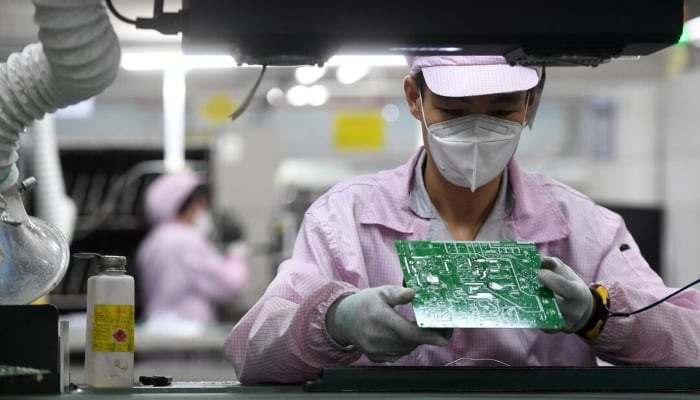 A Chinese employee inspects a circuit board on the controller production line at a factory in Wuhan, Hubei province, China on August 16, 2021. —Reuters