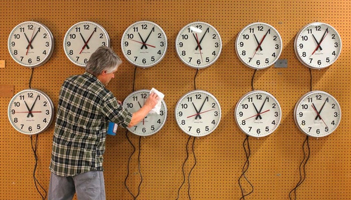 Scott Gow cleans the faces of wall clocks being tested before going to a Capital Grill restaurant at the Electric Time Company in Medfield, Massachusetts on November 1, 2013. — Reuters