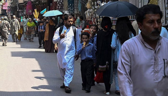 A representational image showing people walking in a market in Lahore. — AFP/File