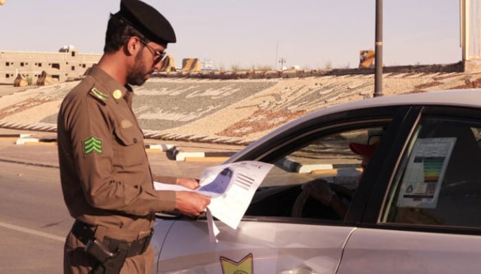 A security official is checking documents of a person in Saudi Arabia. —SPA/ File