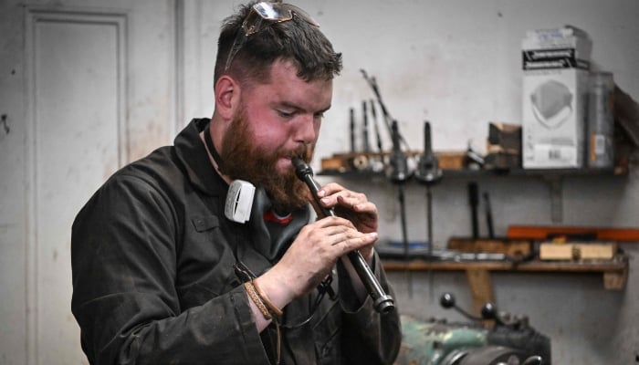 Artisan bagpipe maker Ruari Black tests a bagpipe chanter in the workshop of Kilberry Bagpipes in Edinburgh, on October 7, 2024. —AFP