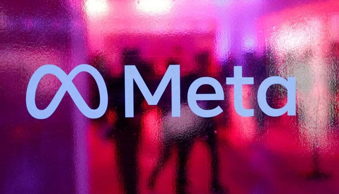 People walk behind a Meta Platforms logo during a conference in Mumbai, India, September 20, 2023. — Reuters