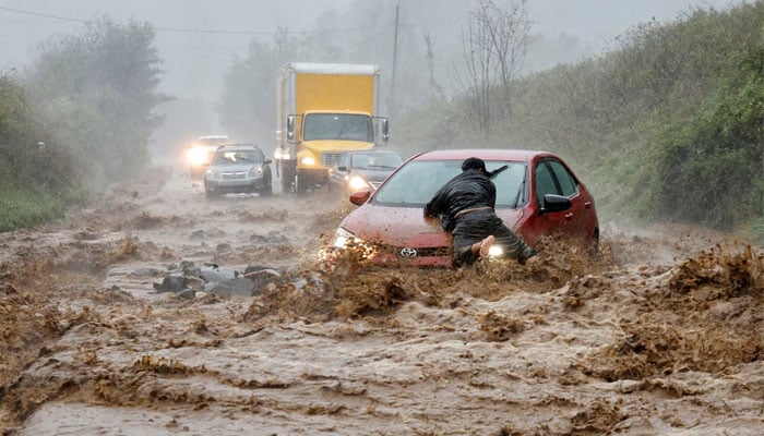 A local resident helps free a car that became stranded in a stretch of flooding road as Tropical Storm Helene strikes, on the outskirts of Boone, North Carolina, September 27, 2024. — Reuters