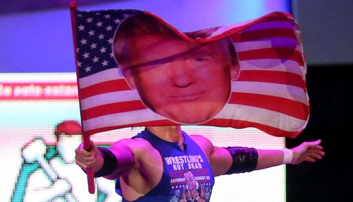 Sam Adonis waves a flag with Trumps face during a wrestling fight — Reuters.