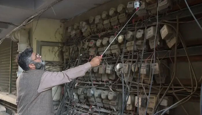 An employee of the state-run Islamabad Electric Supply Company, takes a meter reading with his smartphone at a commercial building in Islamabad. — AFP/File