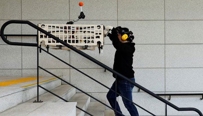 A graduate student of Mechanical Design and Robot Engineering at Seoul National University of Science and Technology, demonstrates the aerial transportation platform Palletrone on stairs at the Seoul Tech in Seoul, South Korea, on October 10, 2024. — Reuters