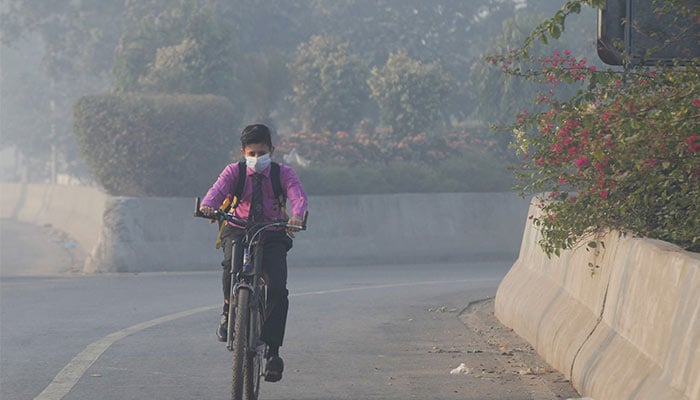 Student rides a bicycle to school amid dense smog in Lahore, November 24, 2021. — Reuters