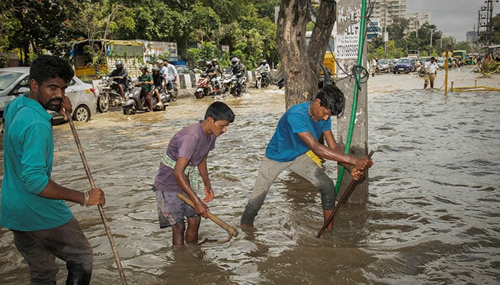 Workers try to open a manhole at a flooded street after heavy rains in Bengaluru, India, October 22, 2024. — Reuters