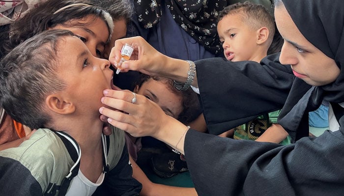 A polio worker administers vaccine to a child. — Reuters/File