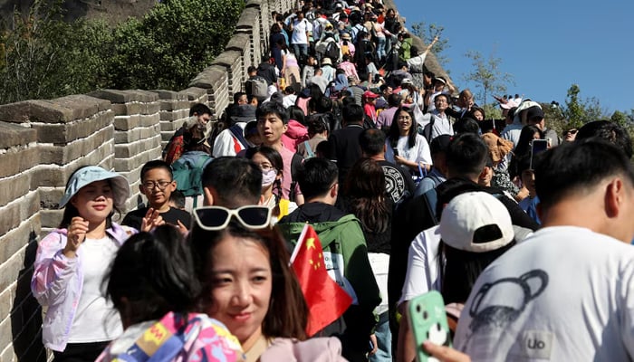 A woman poses for pictures amid tourists visiting the Great Wall in Beijing, China October 1, 2023. — Reuters