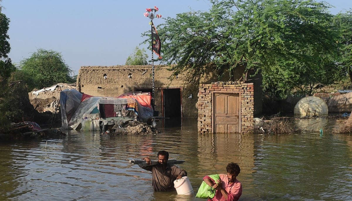 People carry their belongings out from their flooded home in Sindhs Shikarpur district, on August 31, 2022. — AFP