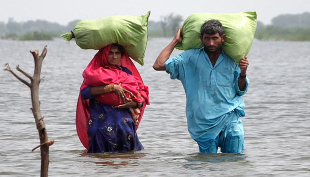 A couple carries their belongings as they wade through flood waters in the village of Ali Nawaz Khuso, Badin district in Sindh. —Reuters/File