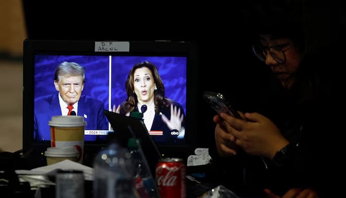 A journalist uses the phone as a screen showing the presidential debate, as Republican presidential candidate former US President Donald Trump and Democratic presidential candidate US Vice President Kamala Harris attend a presidential debate hosted by ABC in Philadelphia, Pennsylvania, United States, September 10, 2024. – Reuters