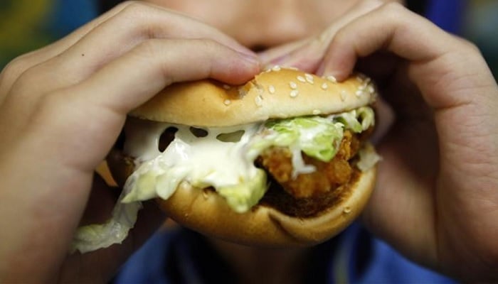 A boy poses with a chicken burger at a fast food outlet in Taipei. — Reuters/File