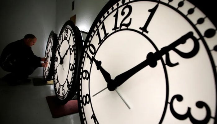 The image shows a man adjusting a clock. — Reuters/File