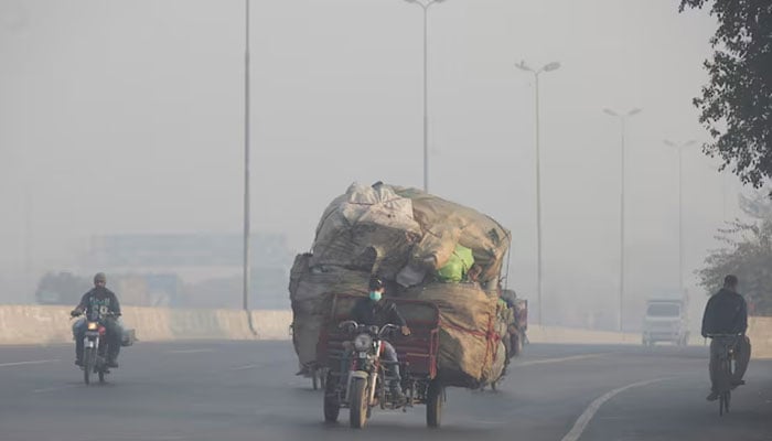 A man rides a motor tricycle, loaded with sacks of recyclables, amid dense smog in Lahore, Pakistan November 24, 2021. — Reuters