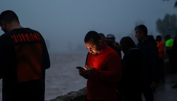 A man checks his mobile phone, after alerts were sent out to Valencia residents asking them to avoid travelling by road in the province, after torrential rains caused flooding in the town of Carlet, Spain, October 30, 2024. — Reuters