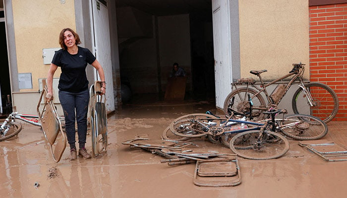 A woman carries out folding chairs caked in mud after torrential rains caused flooding in La Alcudia, Valencia region, Spain, October 30, 2024. — Reuters