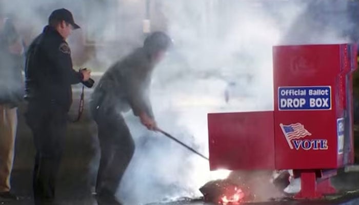 First responders remove the burning contents of a ballot box, used to collect early votes ahead of the US election on November 5, after it was set on fire in a suspected arson in Vancouver, Washington, US on October 28, 2024 in a still from Reuters video