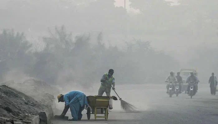 Commuters make their way through a road amid smoggy conditions in Lahore on October 23, 2024. — AFP