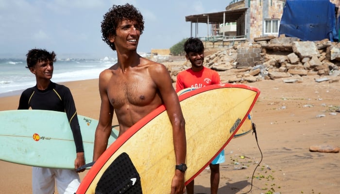 Attiq Ur Rehman, 21, walks with his teammates along the beach as they prepare to surf at Turtle Beach in Karachi, on September 4, 2024. —Reuters