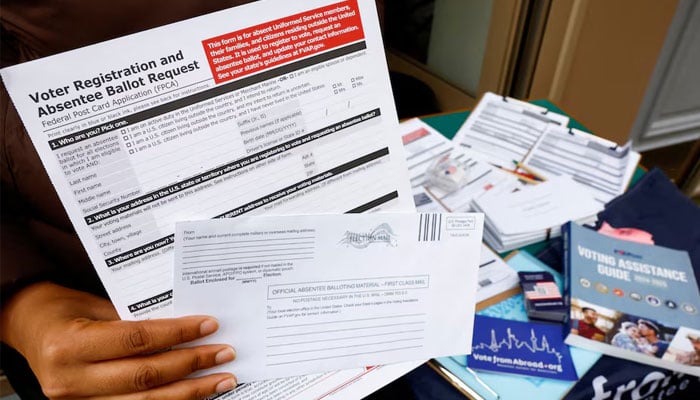 A US citizen abroad voter holds a voter registration and absentee ballot request form and an envelope which will contain an official absentee balloting material at a stand set up outside a cafe by Democrats Abroad volunteers to help Americans living in Paris to navigate the bureaucracies of state and local election laws, in Paris, France, October 21, 2024. — Reuters