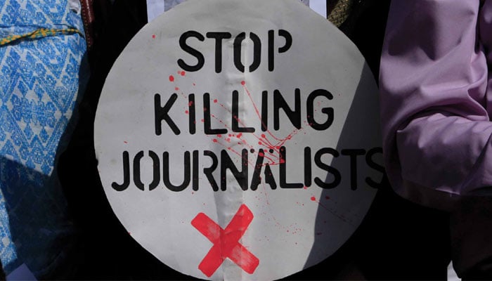 A Pakistani journalist holds a sign during a demonstration to condemn attacks against journalists in Islamabad 7 April, 2014. — Reuters