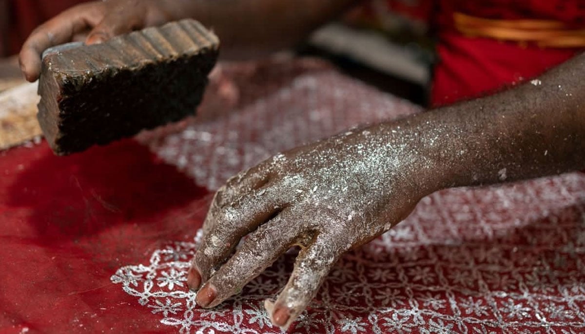 An artisan making chaapa on a red-coloured fabric using a wooden block in Bihar, India. — Photo by Afzal Adeeb Khan