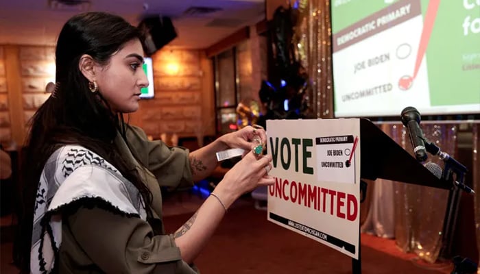 Activist Natalia Latif tapes a Vote Uncommitted sign on the speakers podium during a primary election night gathering in Dearborn, Michigan, on February 27, 2024. — Reuters/File