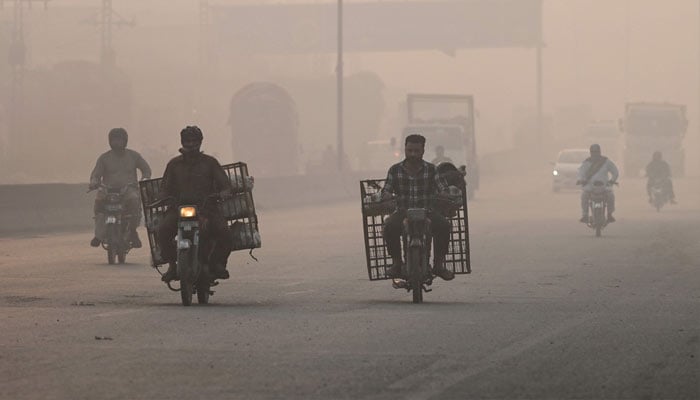 Commuters make their way amid smog in Lahore on November 2, 2024. — AFP