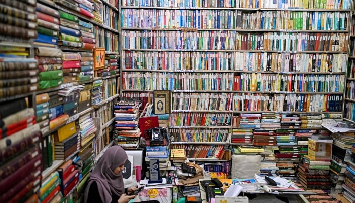 This photograph taken on October 22, 2024 shows a student sitting amid Urdu books stacked at the Hazrat Shah Waliullah public library, in Urdu Bazar in the old quarters of Delhi. —AFP