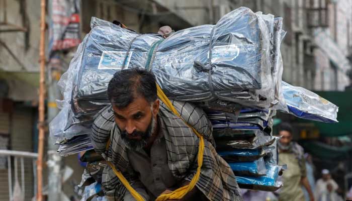 A labourer delivers packs of fabrics to a market in Karachi. — Reuters/File