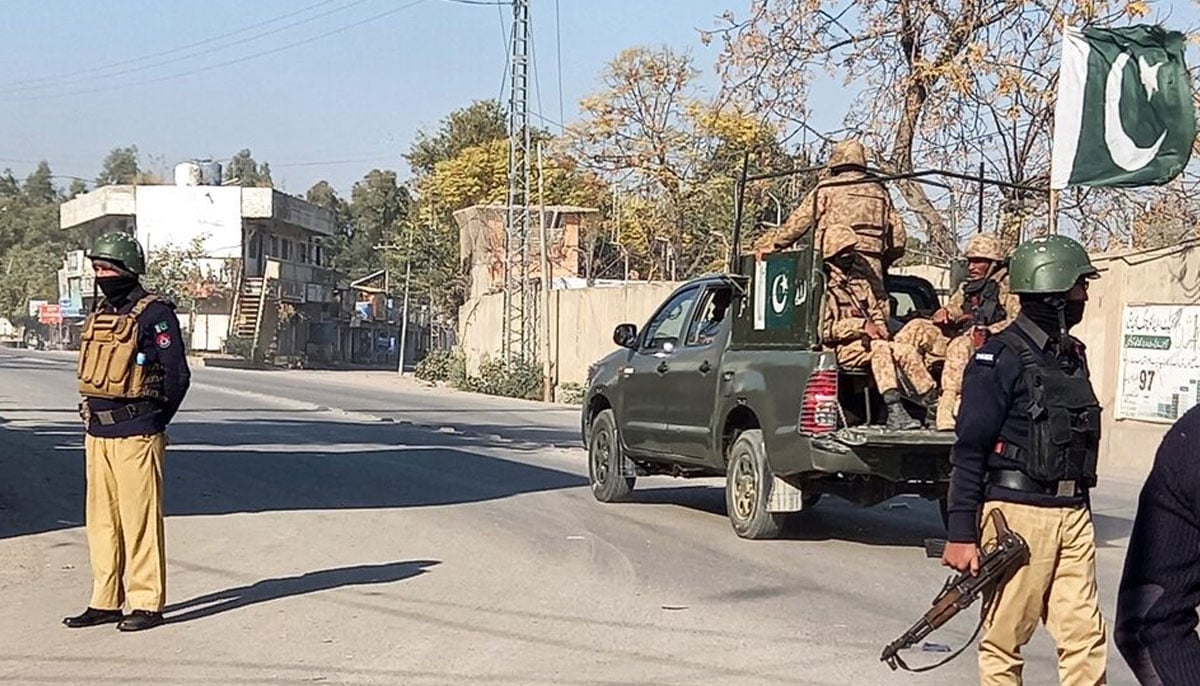 An Army vehicle patrols, past police officers stand guard along a road, near cantonment area in Bannu, December 21, 2022. — Reuters