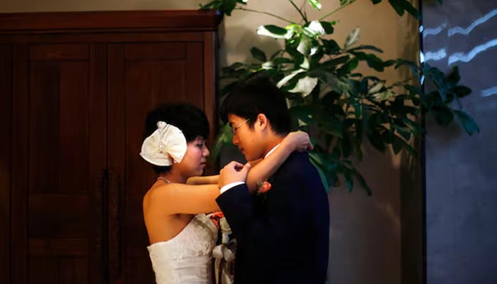 A couple prepares to participate in a staged mass wedding, organised as part of a matchmaking event to inspire singles to get married, in a suburban area of Shanghai May 18, 2013. — Reuters