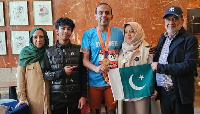 Pakistani runner Danish Elahi poses with his family while holding a Pakistani flag after the New York City Marathon in New York, US, on November 3, 2024. — Supplied