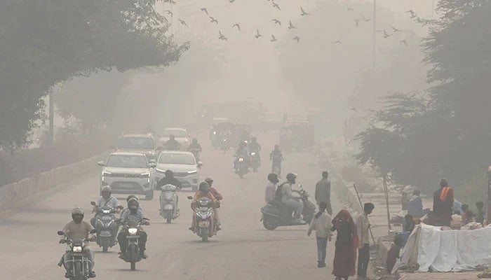 People and vehicles are seen on a road amidst the morning smog in New Delhi, India, November 8, 2023. — Reuters